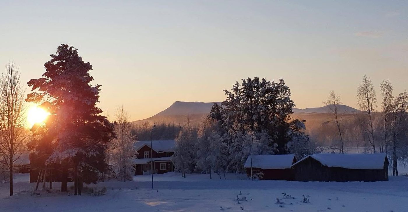 Vintermorgon i Hede med snötäckta hus och fjäll i soluppgången